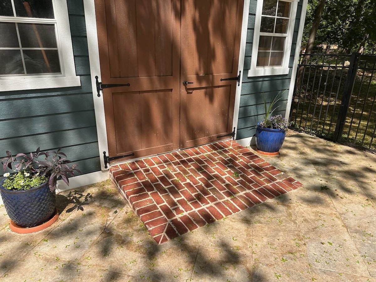 Brick entry step leading to brown double shed doors at a Ridgewood, NJ custom home.