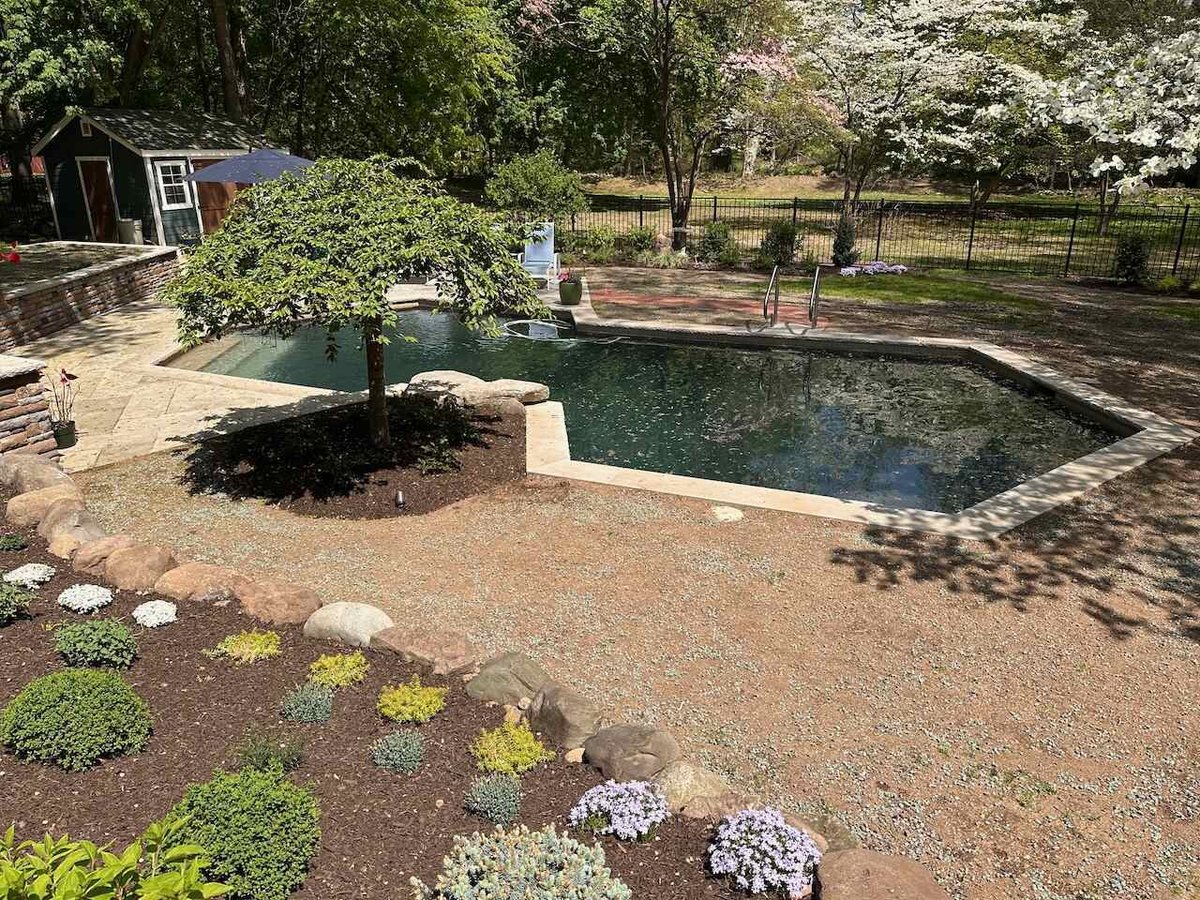 Custom inground pool surrounded by landscape beds and stone patio in Ridgewood, NJ by Fairmount Heights Homes.