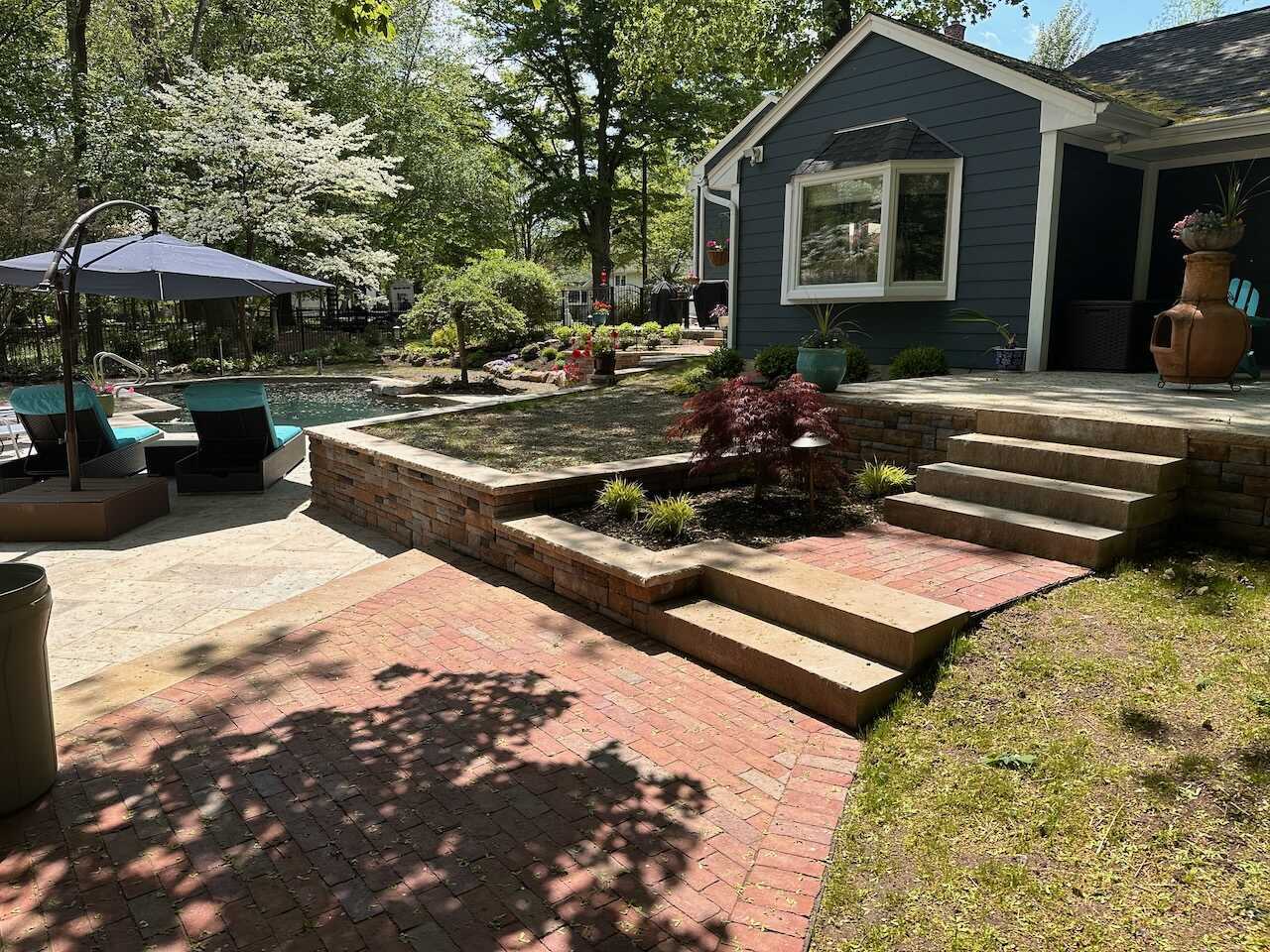 Elevated patio and terraced garden overlooking pool area in Ridgewood, NJ by Fairmount Heights Homes.