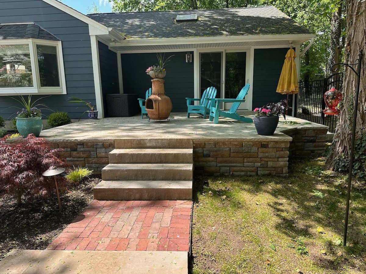Elevated stone patio with red brick stairs and potted plants in Ridgewood, NJ by Fairmount Heights Homes.