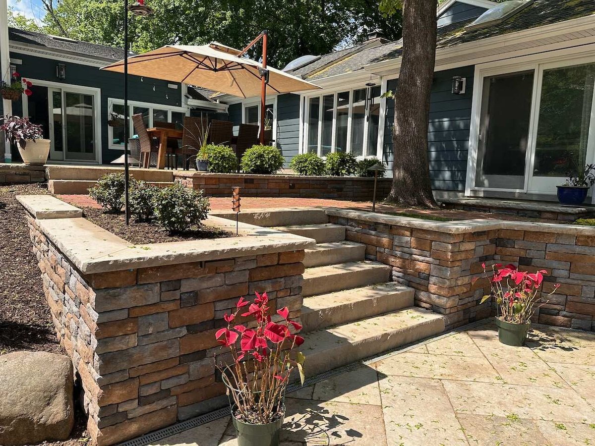 Elevated stone steps and retaining walls with garden beds at a Ridgewood custom home by Fairmount Heights Homes.