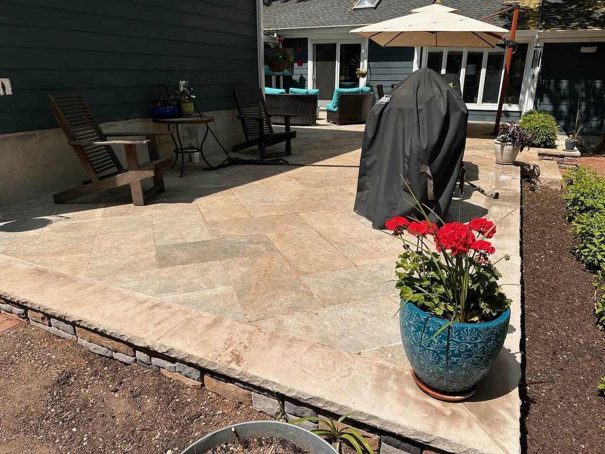 Outdoor living space with natural stone flooring and lounge furniture at Ridgewood custom home.