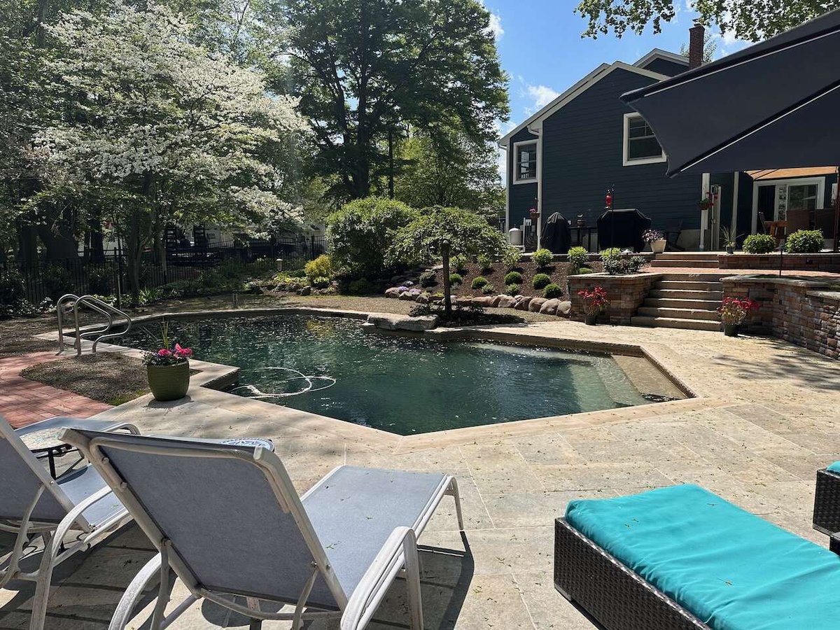 Poolside patio with lounge chairs and lush landscaping at Ridgewood custom home by Fairmount Heights Homes.