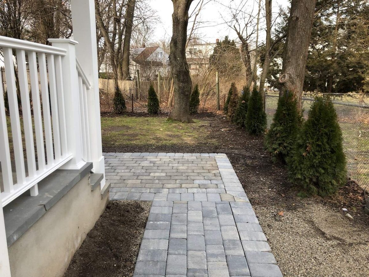 Backyard paver patio with white railing in Ridgewood, NJ custom home by Fairmount Heights Homes.