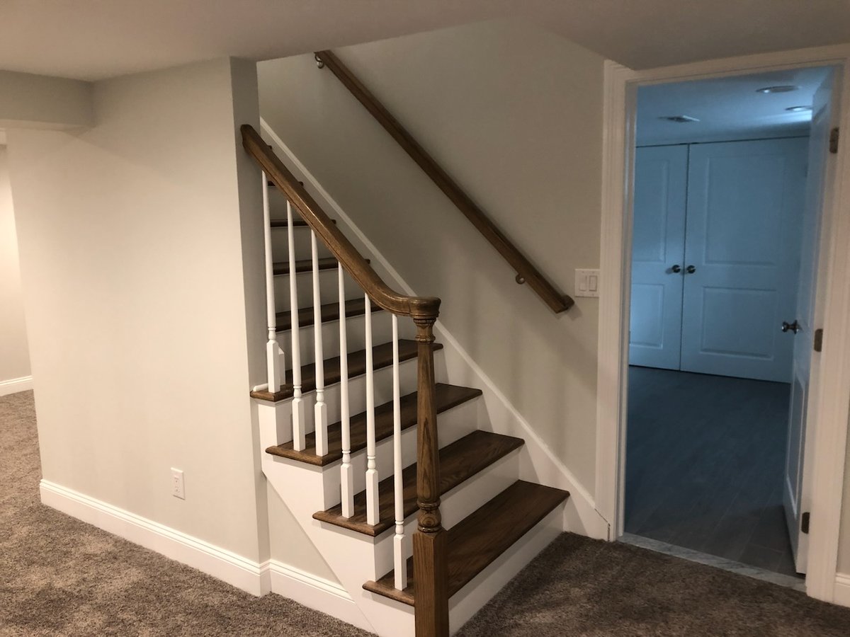 Basement staircase with oak handrail and white spindles in Ridgewood, NJ by Fairmount Heights Homes.