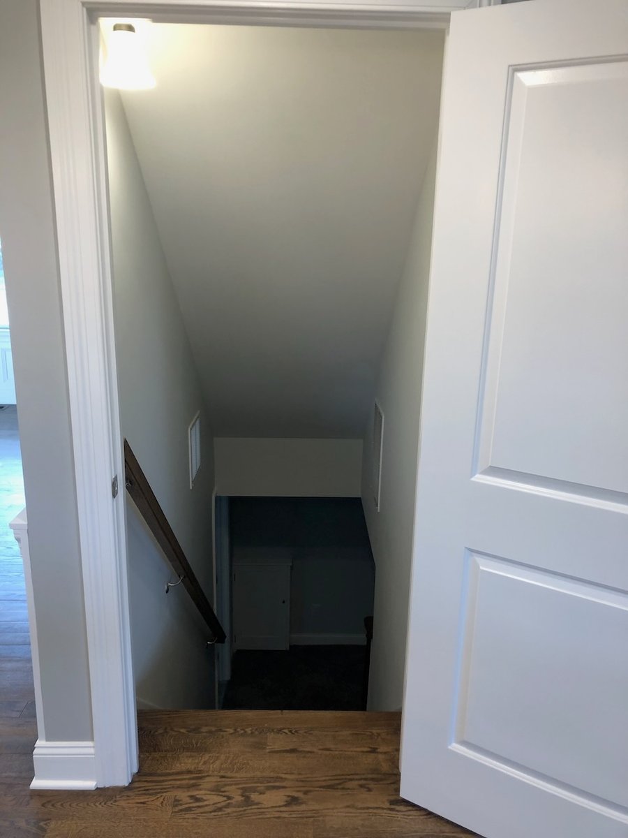Basement stairway with wood handrail and white trim in Ridgewood custom home.