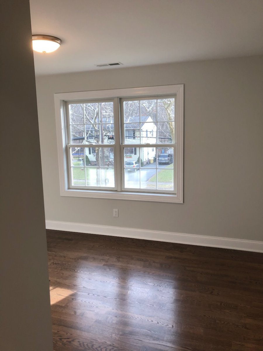 Bright bedroom with wide window and hardwood floors in Ridgewood home by Fairmount Heights Homes.