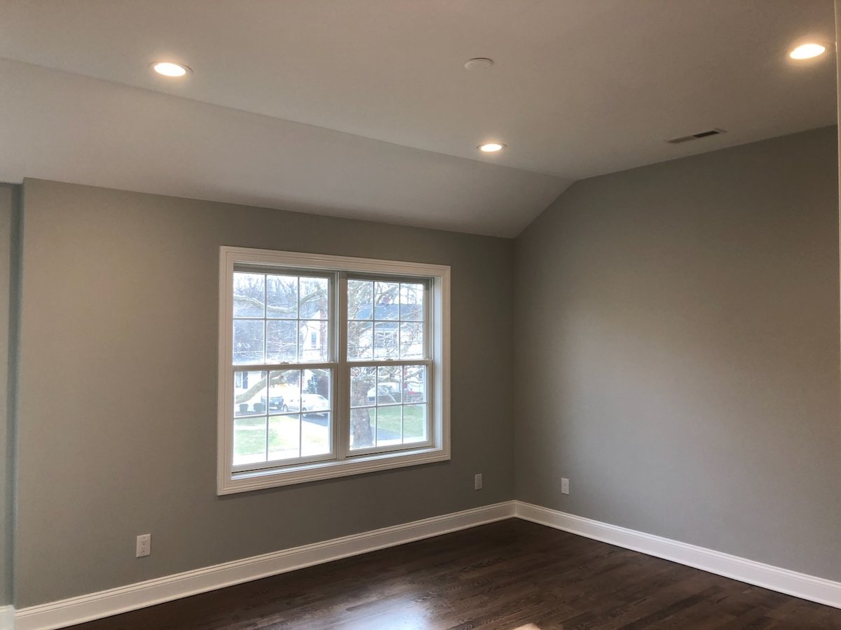 Bright upstairs bedroom with vaulted ceiling and large window in Ridgewood, NJ custom home.