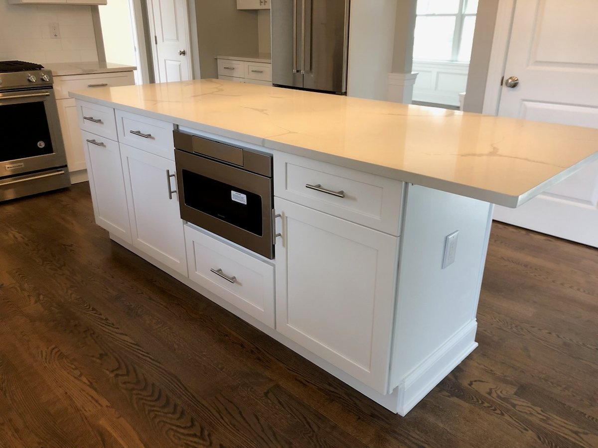 Center kitchen island with built-in microwave and quartz countertop in Ridgewood home by Fairmount Heights Homes.