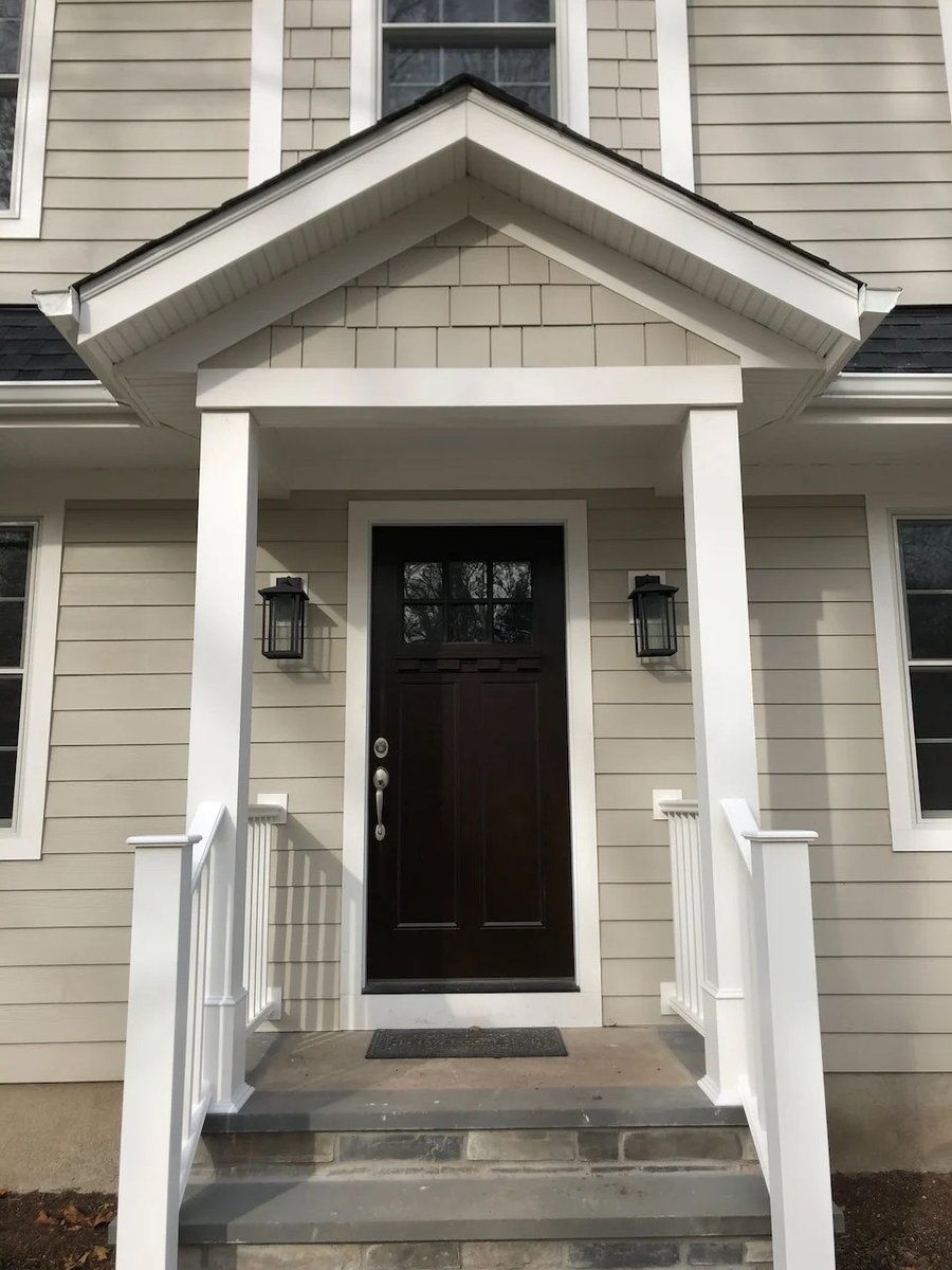 Close-up of custom home entry with dark wood door and white porch columns by Fairmount Heights Homes in Ridgewood, NJ.