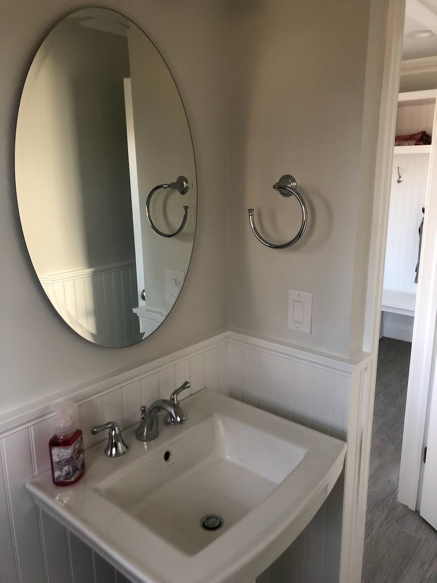 Compact powder room design with white wainscoting and chrome towel ring by Fairmount Heights Homes in Ridgewood, NJ.