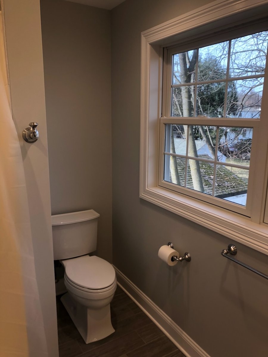 Compact toilet space beside large window in Ridgewood custom home by Fairmount Heights Homes.