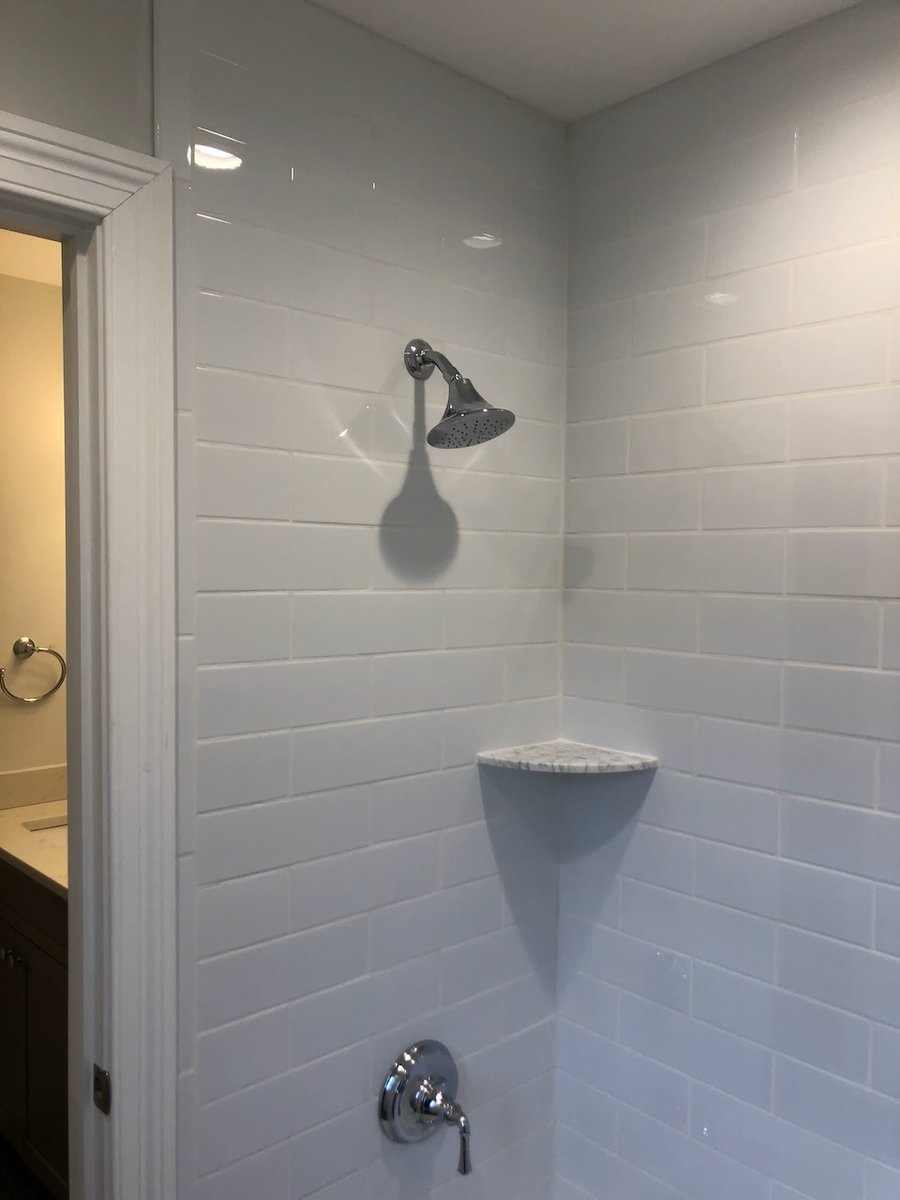 Custom tiled shower with corner shelf and chrome fixtures in Ridgewood home by Fairmount Heights Homes.