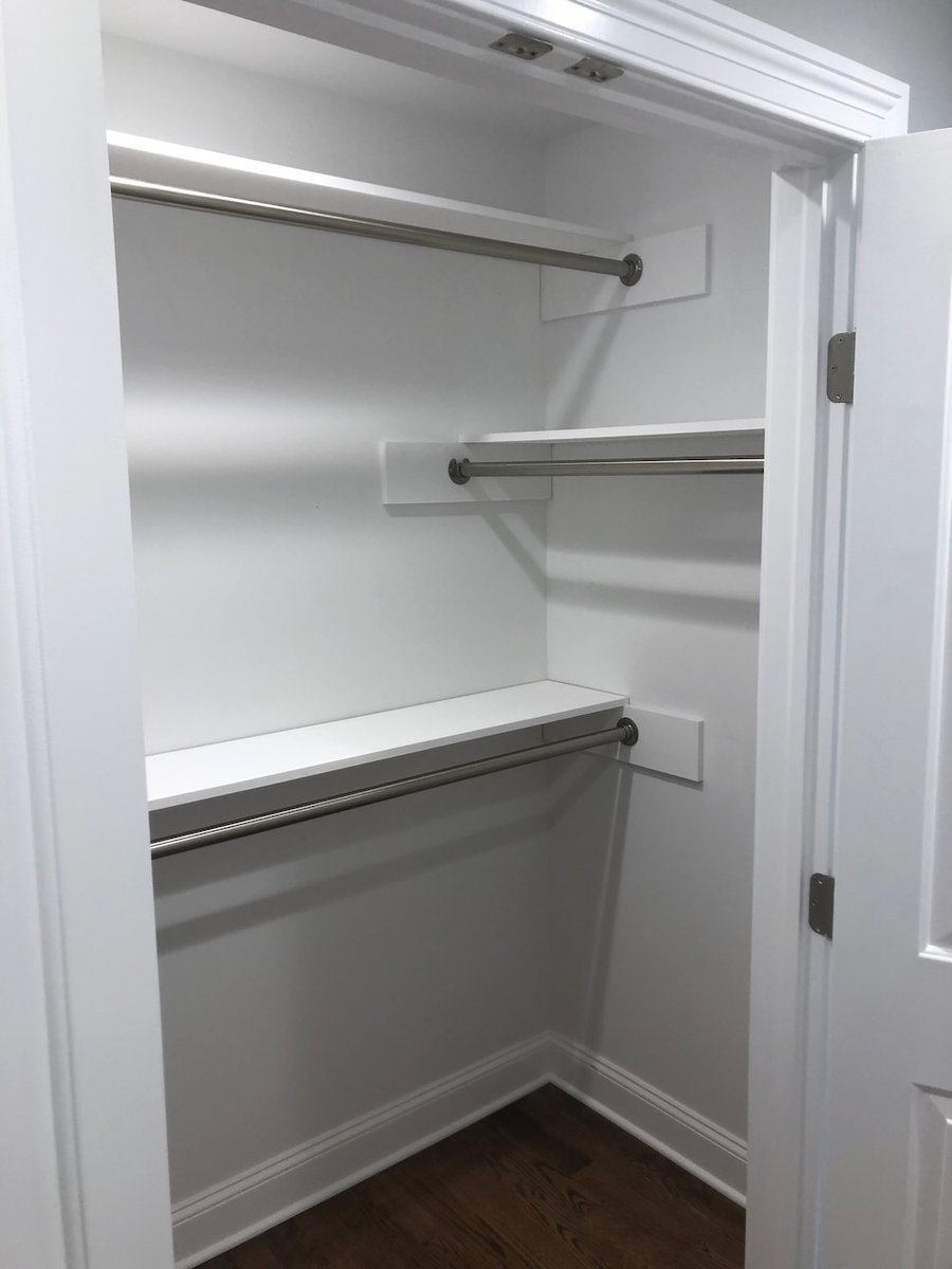Custom walk-in closet with double hanging rods and white shelving in Ridgewood, NJ home.