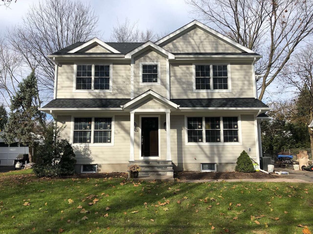 Exterior view of newly built two-story custom home with beige siding in Ridgewood, NJ.