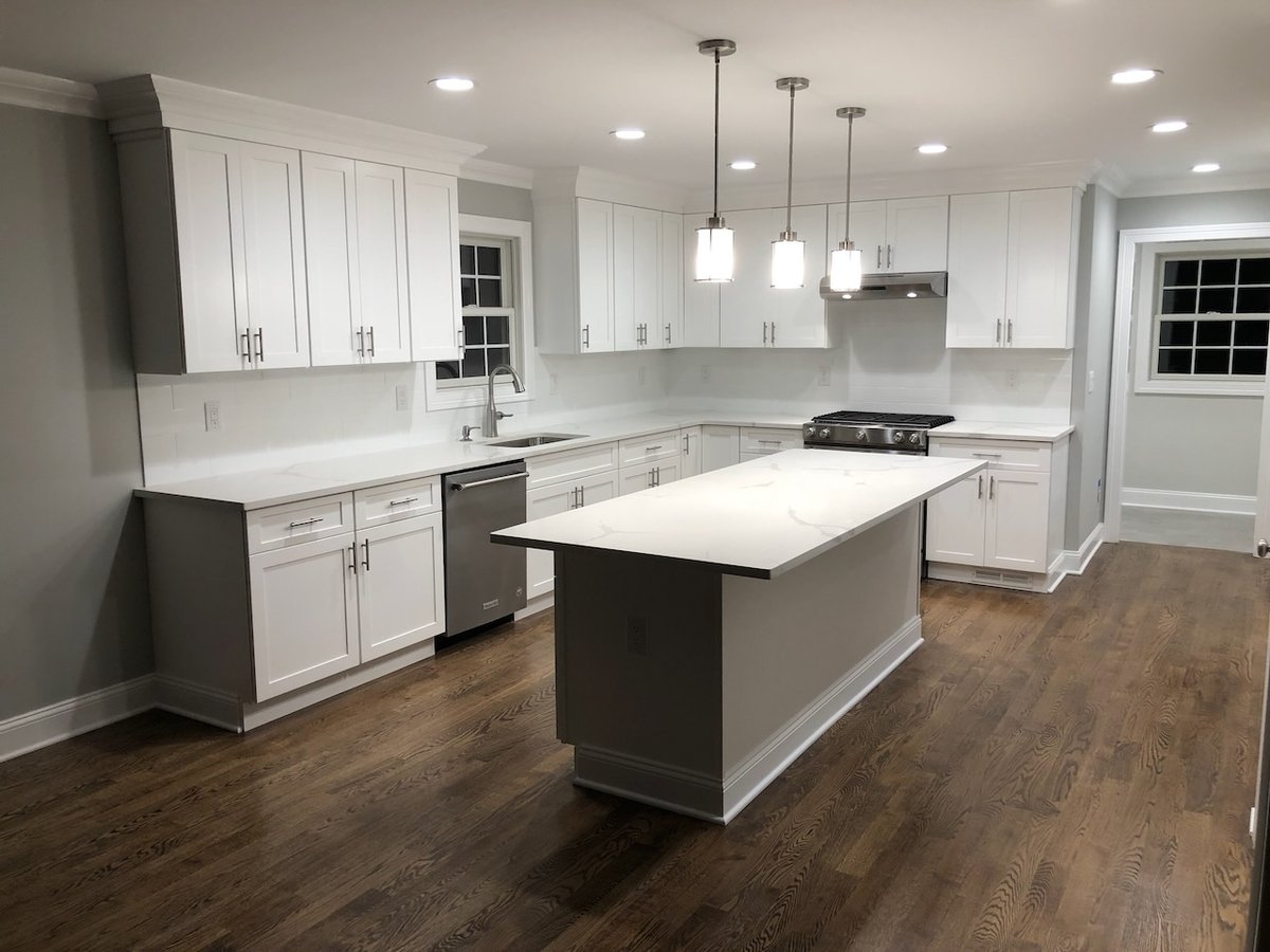 Finished white kitchen with large center island and modern lighting in Ridgewood custom home.