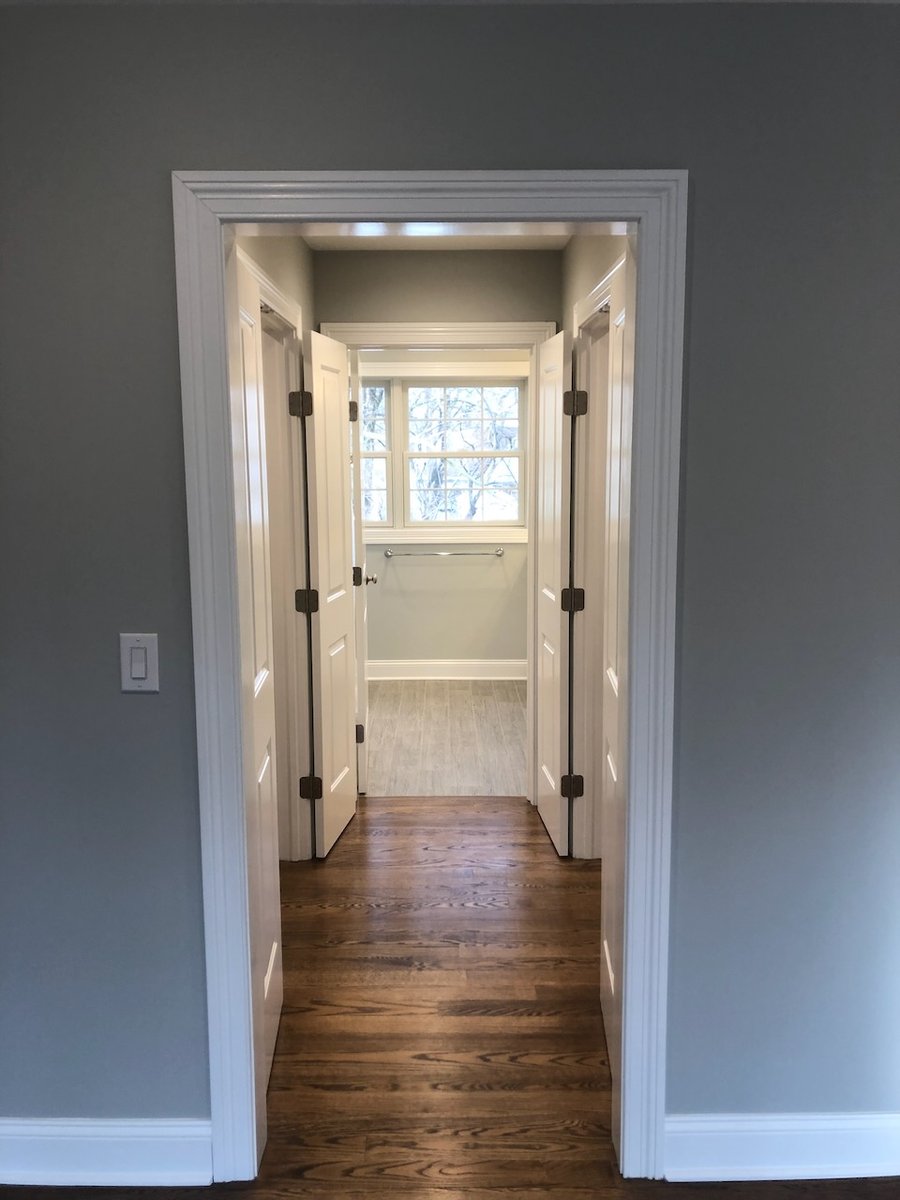 Hallway leading to bathroom with framed double doors and wood floors in Ridgewood, NJ.