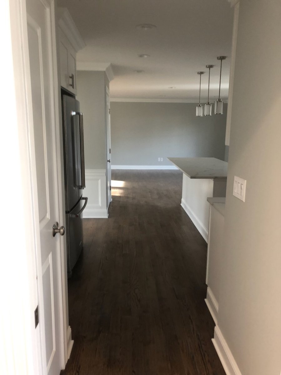 Hallway view into kitchen with hardwood floors and pendant lights in Ridgewood, NJ custom home.