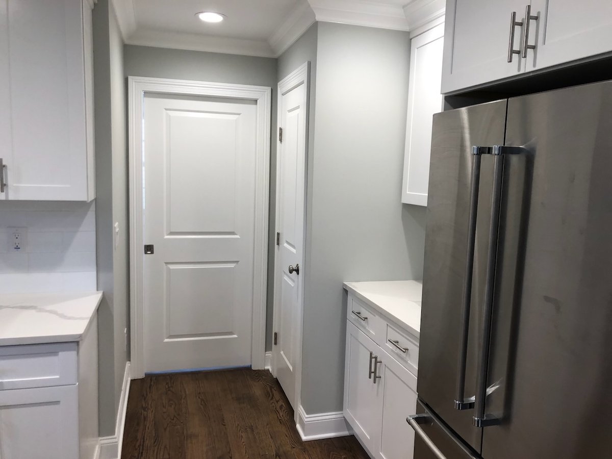Kitchen hallway with white cabinetry and stainless fridge in Ridgewood custom home by Fairmount Heights Homes.