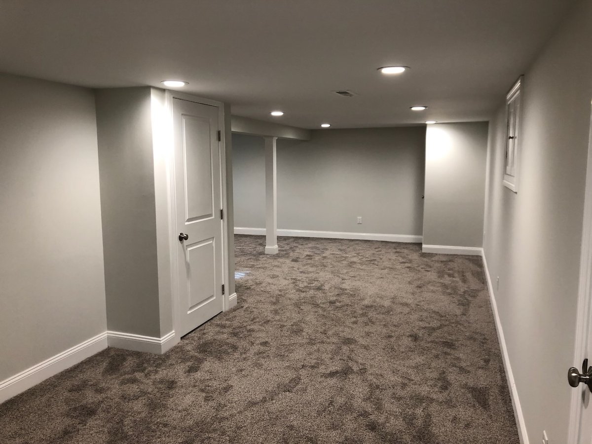Long basement room with neutral carpet and closet door by Fairmount Heights Homes in Ridgewood.
