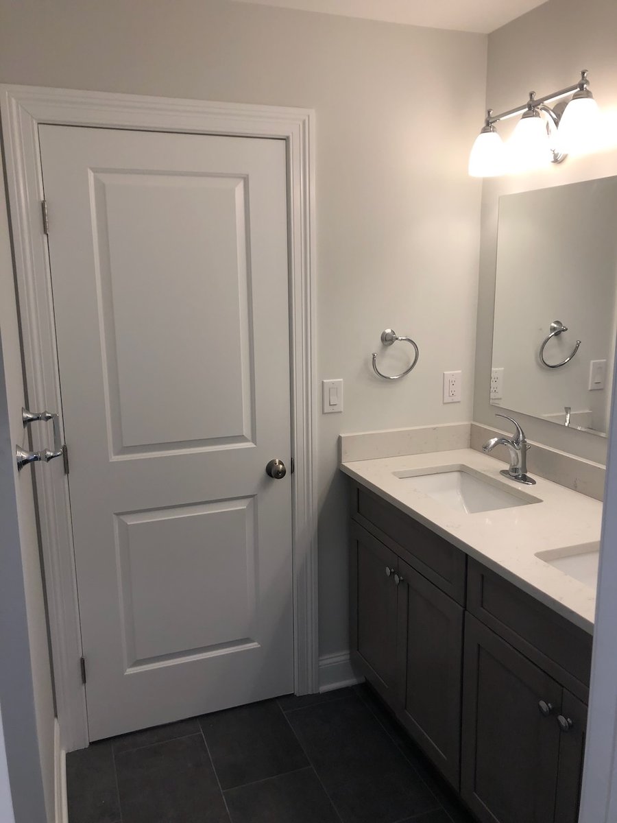 Modern bathroom vanity with light countertop and mirror in Ridgewood, NJ by Fairmount Heights Homes.