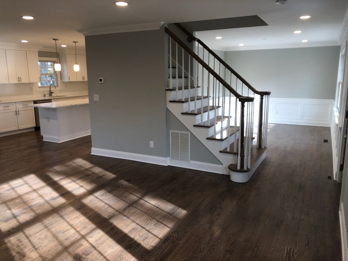 Open-concept main floor with hardwood floors and white staircase in Ridgewood, NJ custom home.