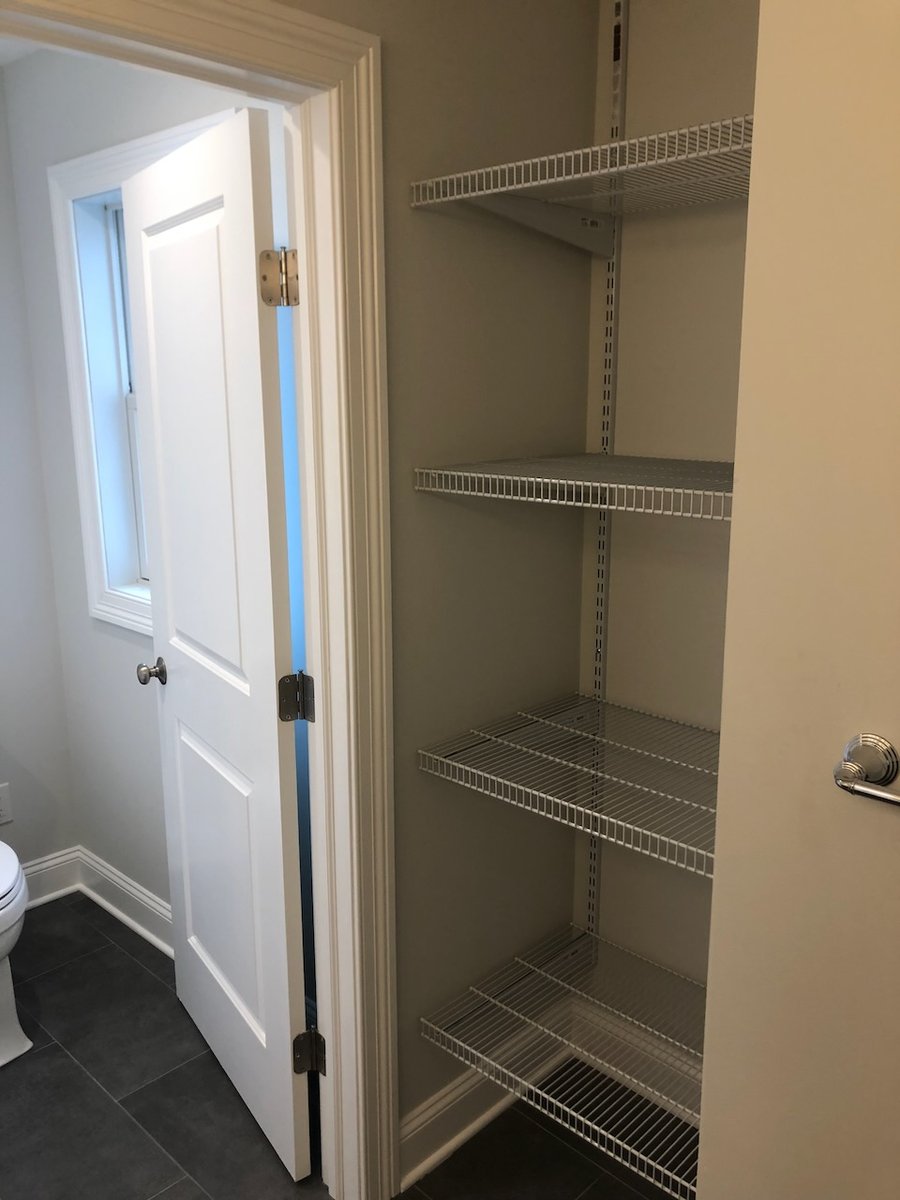 Organized wire shelving inside bathroom closet in Ridgewood custom home by Fairmount Heights Homes.