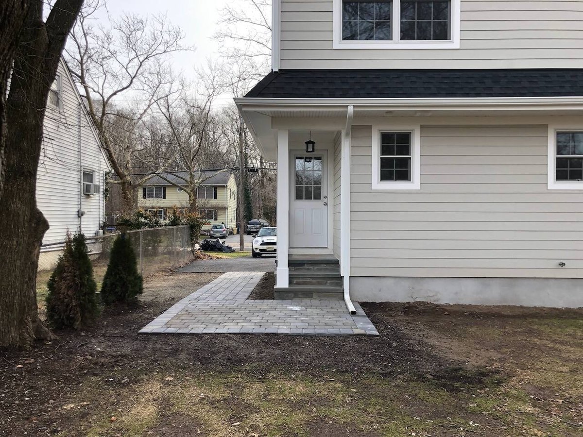 Rear entrance with white door, steps, and pavers at a custom home in Ridgewood, NJ by Fairmount Heights Homes.