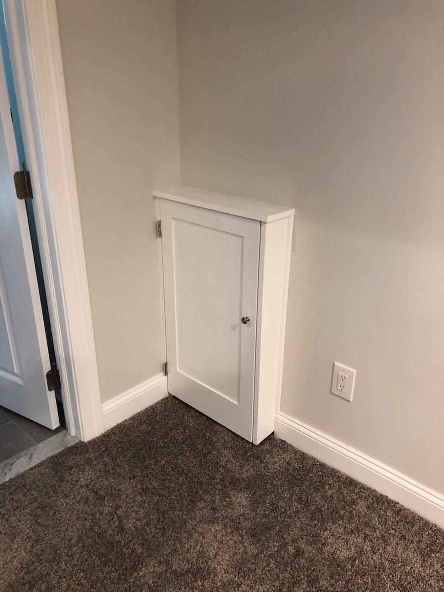 Small white utility cabinet in finished Ridgewood basement by Fairmount Heights Homes.