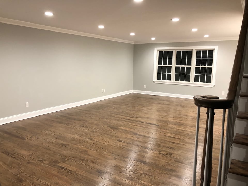 Spacious living room with recessed lighting and wood floors in Ridgewood custom home.