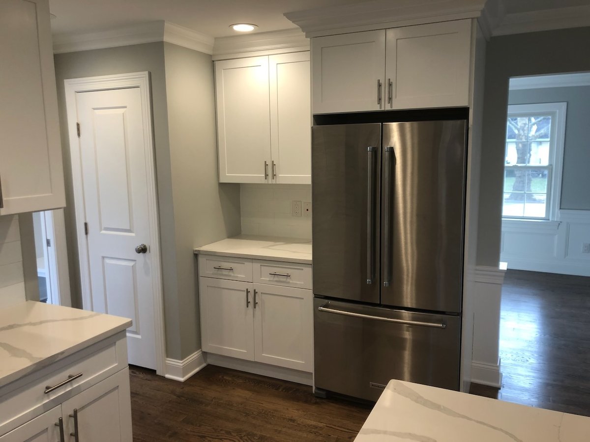 Stainless steel refrigerator built into white shaker cabinetry in Ridgewood, NJ custom kitchen.