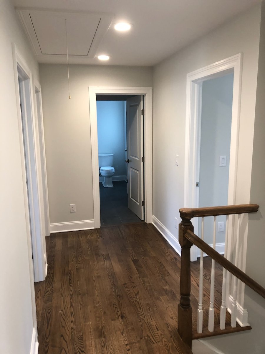 Upstairs hallway with hardwood floors and bathroom view in Ridgewood home by Fairmount Heights Homes.
