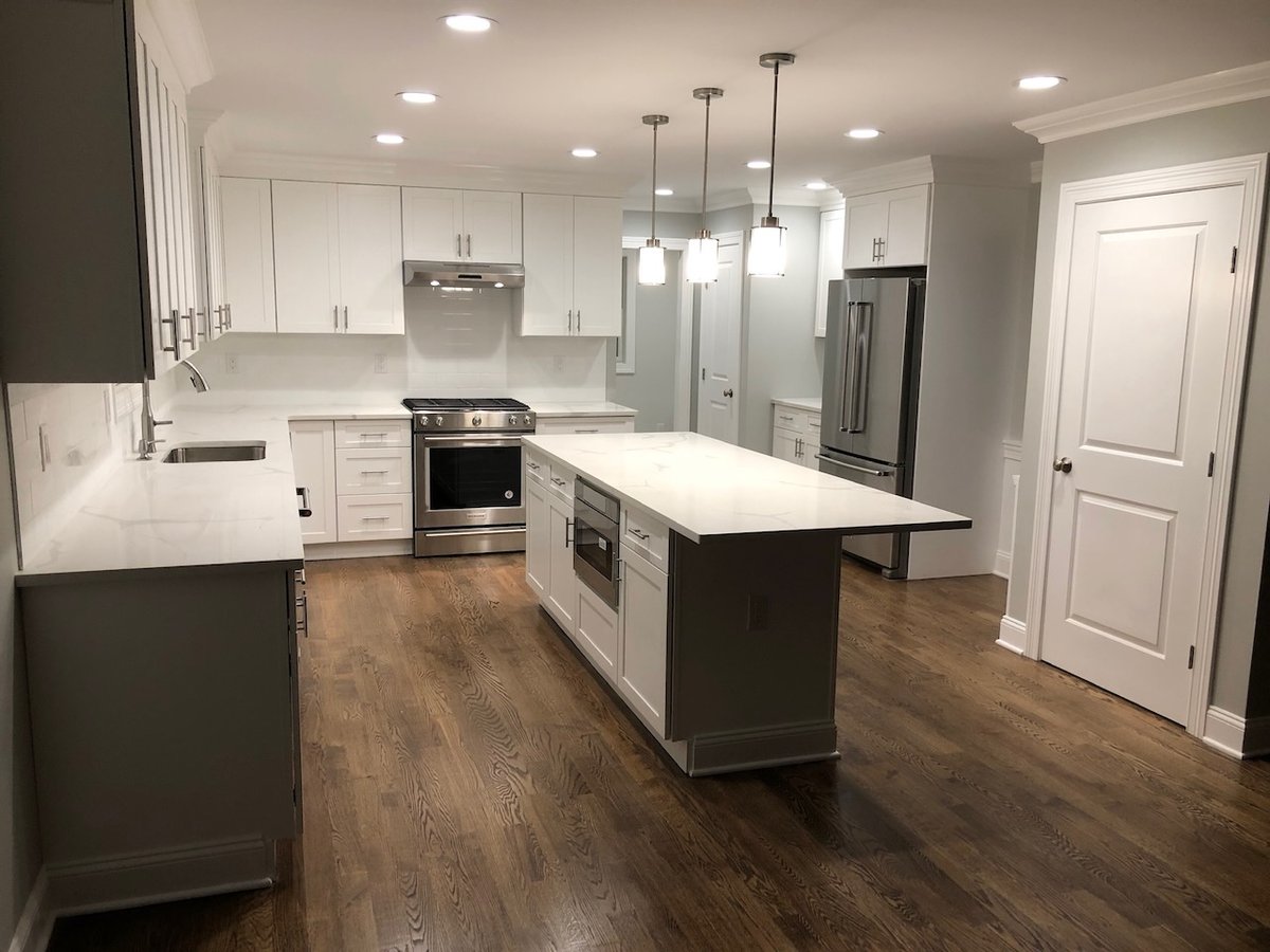 White modern kitchen with large island and stainless steel appliances in Ridgewood custom home.