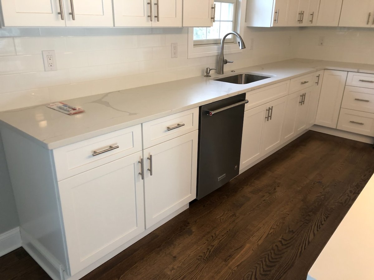 White shaker kitchen cabinets with quartz countertop and stainless dishwasher in Ridgewood home by Fairmount Heights Homes.