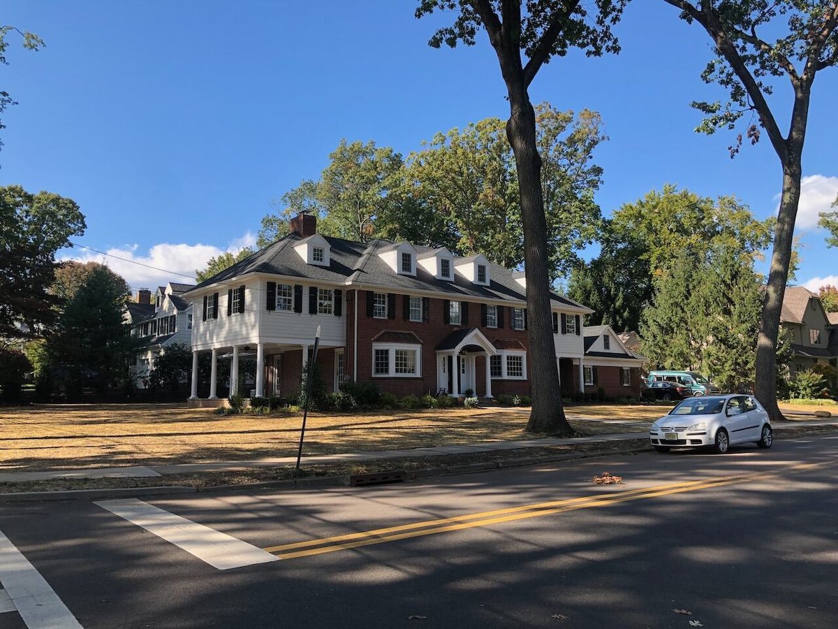 Brick and siding custom home with dormers and black shutters in Ridgewood, NJ by Fairmount Heights Homes.