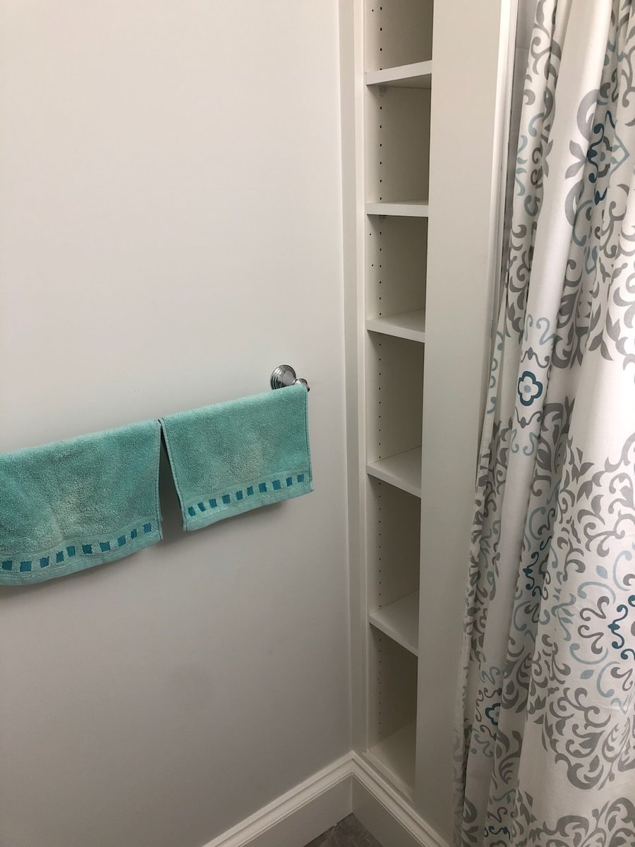 Built-in bathroom shelving with turquoise towel accents in Ridgewood, NJ home by Fairmount Heights Homes.