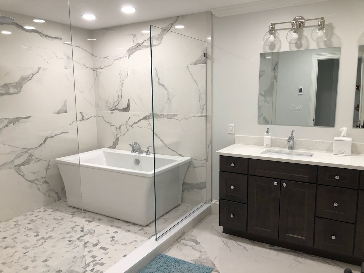 Elegant master bathroom with soaking tub, dark vanity, and marble flooring in Ridgewood, NJ by Fairmount Heights Homes.