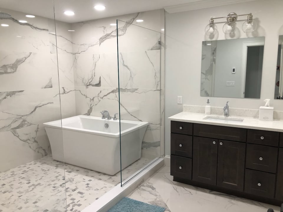 Elegant master bathroom with soaking tub, dark vanity, and marble flooring in Ridgewood, NJ by Fairmount Heights Homes