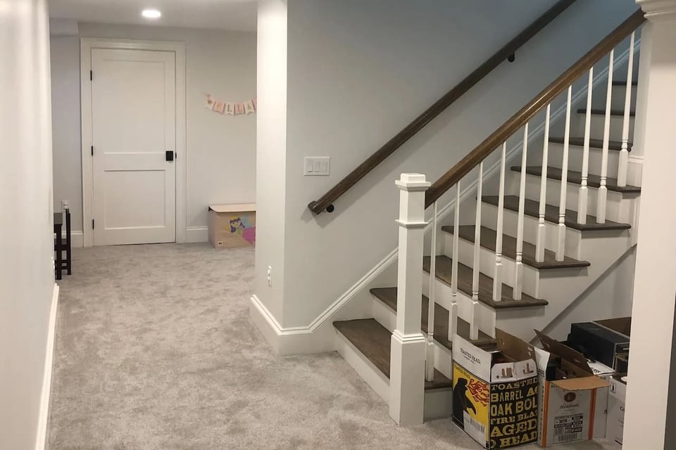 Finished basement with carpeted flooring and wood staircase in Ridgewood, NJ custom home by Fairmount Heights Homes