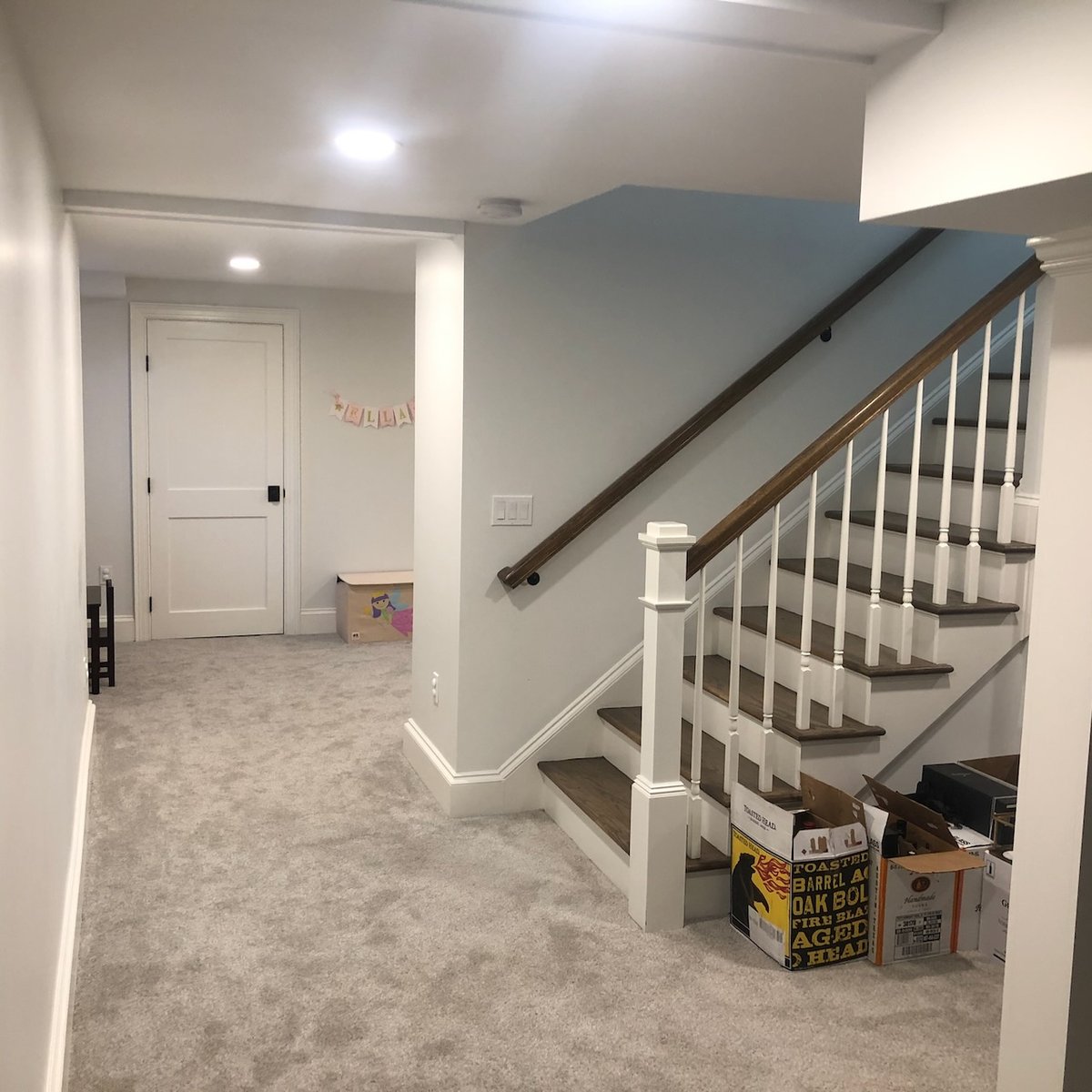 Finished basement with carpeted flooring and wood staircase in Ridgewood, NJ custom home by Fairmount Heights Homes.