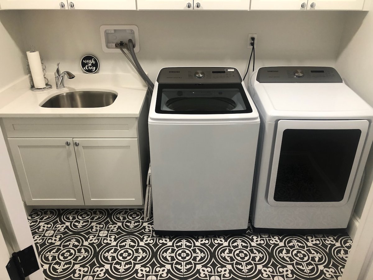 Laundry room with washer, dryer, utility sink, and patterned tile floor in Ridgewood, NJ by Fairmount Heights Homes.