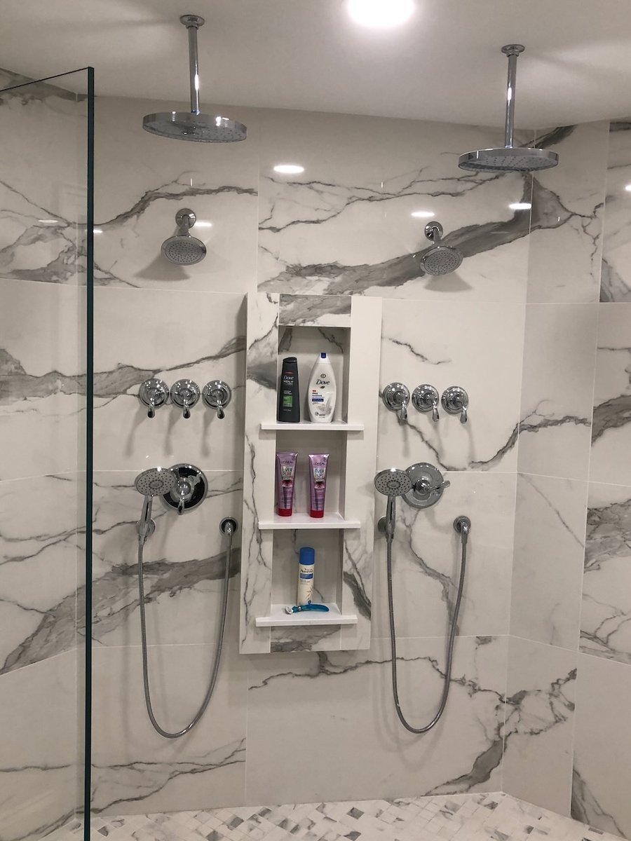 Marble tile shower with built-in niche and dual rain heads in a Ridgewood, NJ custom home by Fairmount Heights Homes.