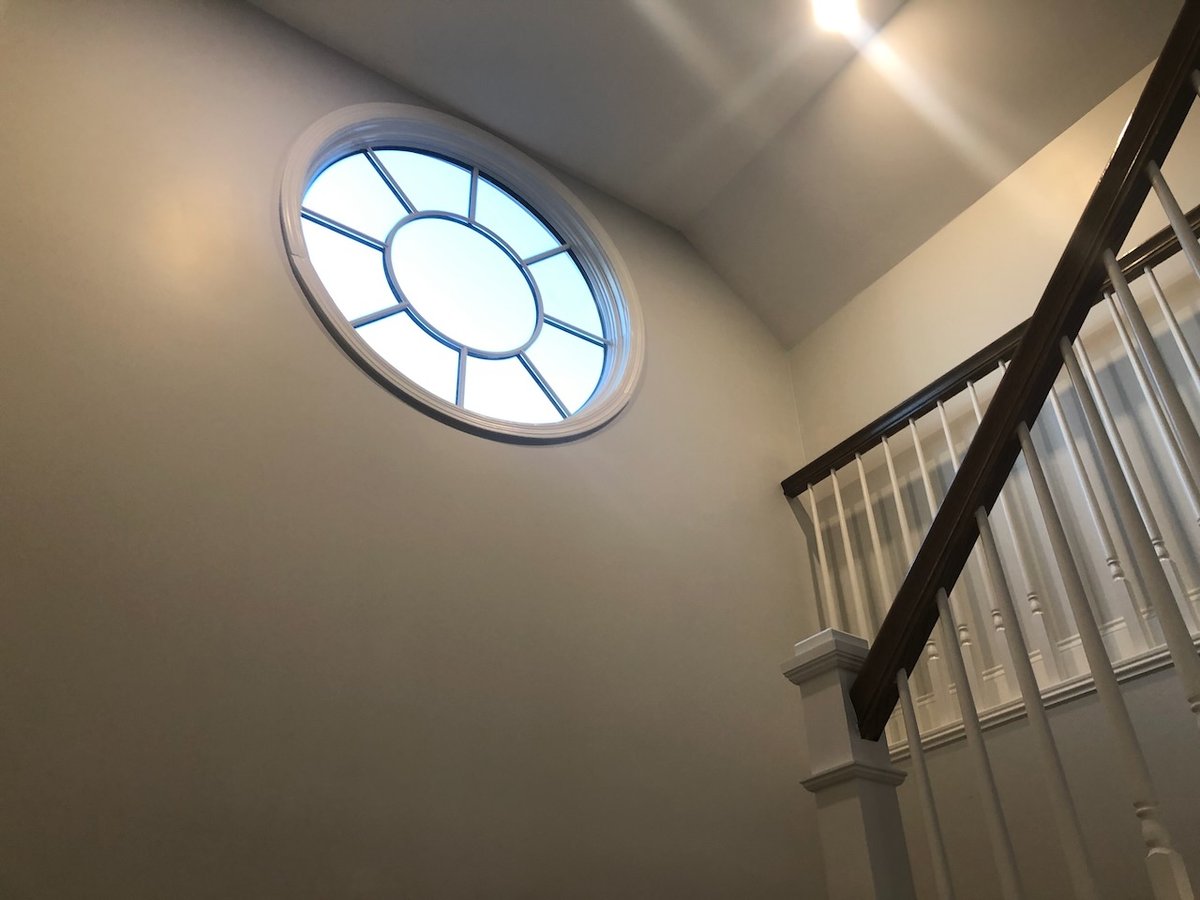 Round accent window above stairwell in Ridgewood, NJ custom home by Fairmount Heights Homes.