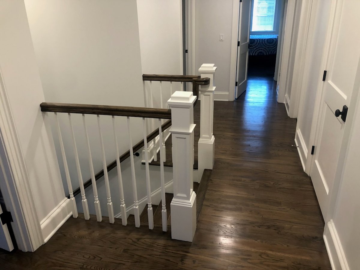 Upper stair landing with wood floors and white balusters in Ridgewood, NJ custom home by Fairmount Heights Homes.