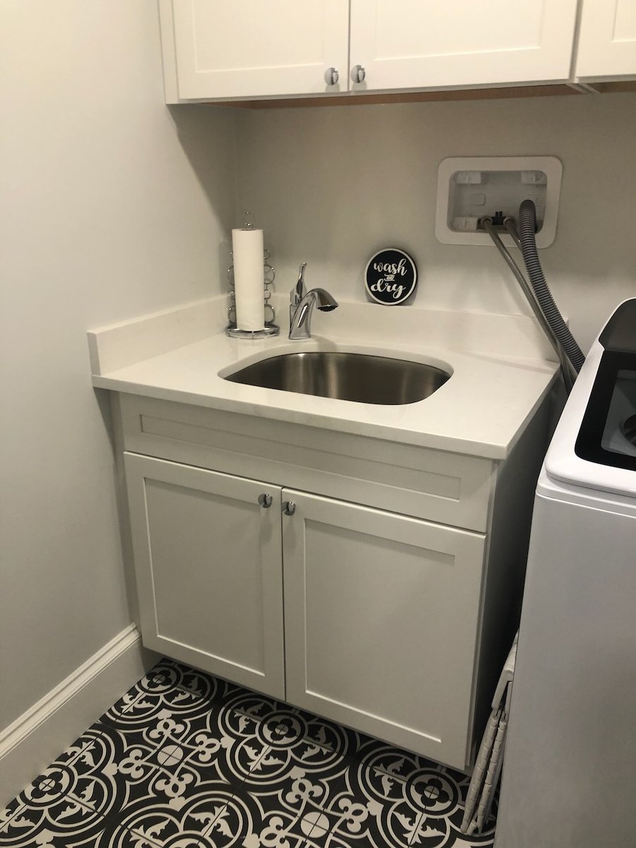 Utility sink area with chrome faucet and storage cabinets in Ridgewood, NJ custom laundry room by Fairmount Heights Homes.