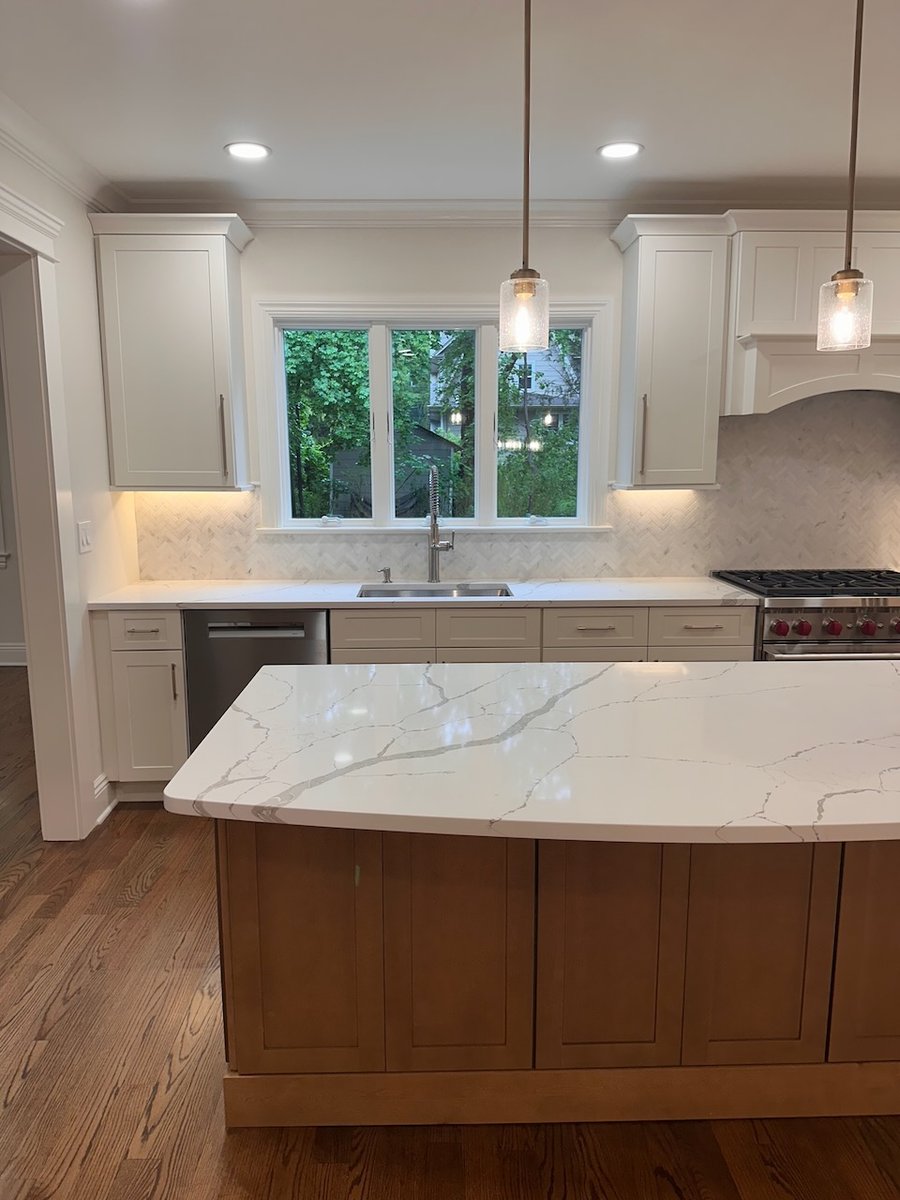 Kitchen island with waterfall-edge quartz countertop and pendant lights by Fairmount Heights Homes in Ridgewood, NJ.