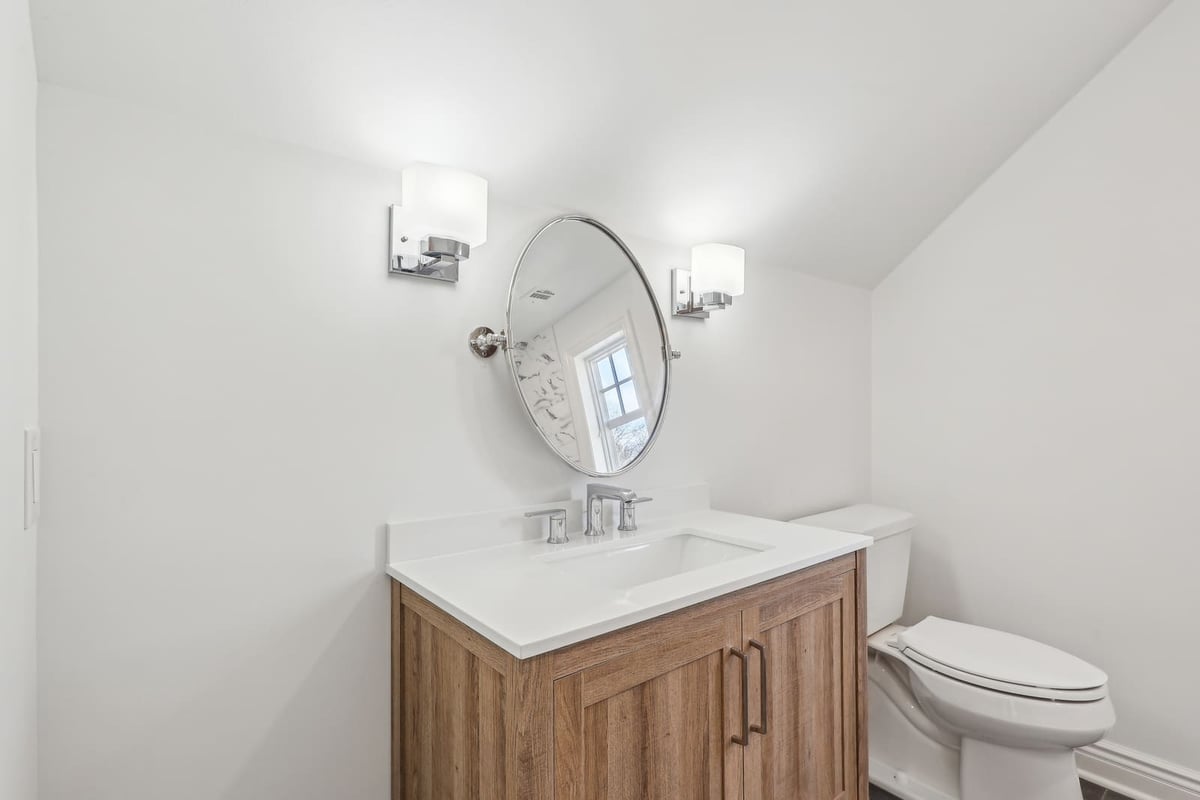 Bathroom in Ridgewood, NJ with wood vanity and oval mirror