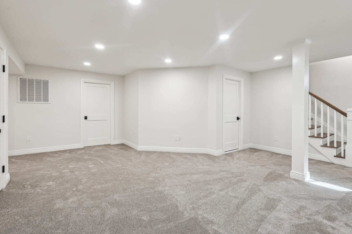 Finished basement in Ridgewood, NJ with carpet, recessed lighting, and stair access