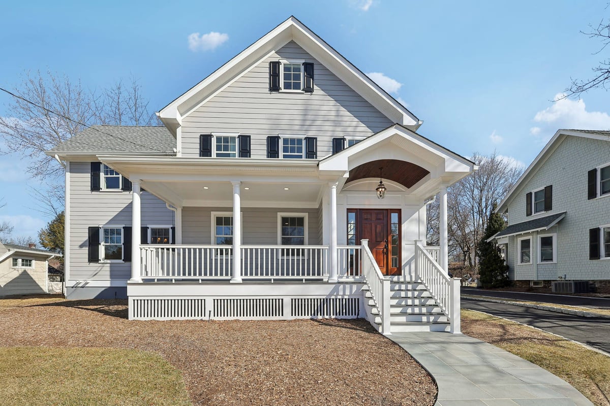 Front exterior of a gray colonial home in Ridgewood, NJ with white trim and a covered porch