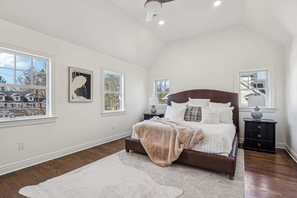 Primary bedroom in Ridgewood, NJ with vaulted ceiling, hardwood floors, and large windows